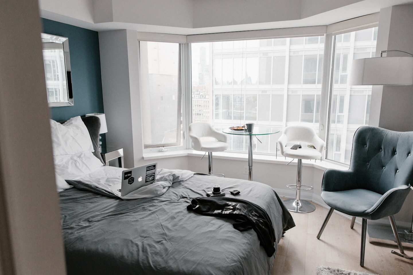 Modern studio apartment with bed, laptop, and city view.
