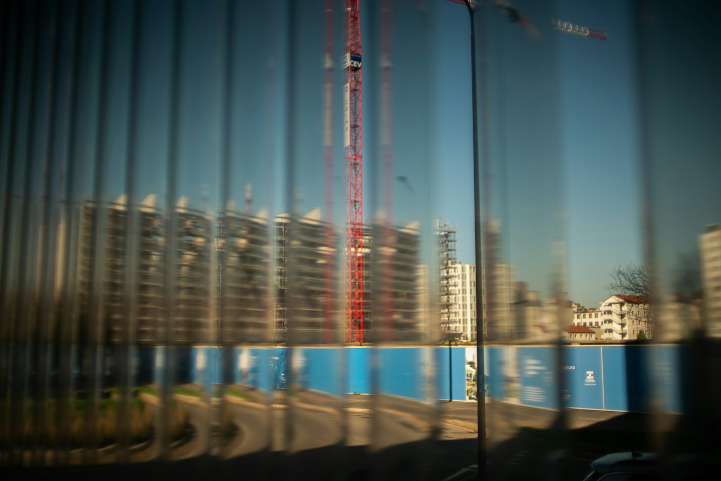 A red tower crane stands over modern buildings under construction.